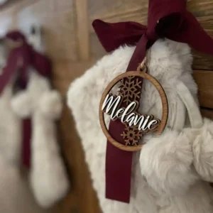 One Layered Wooden Christmas Ornament with the name Melanie and a snowflake design, hanging on a festive stocking.